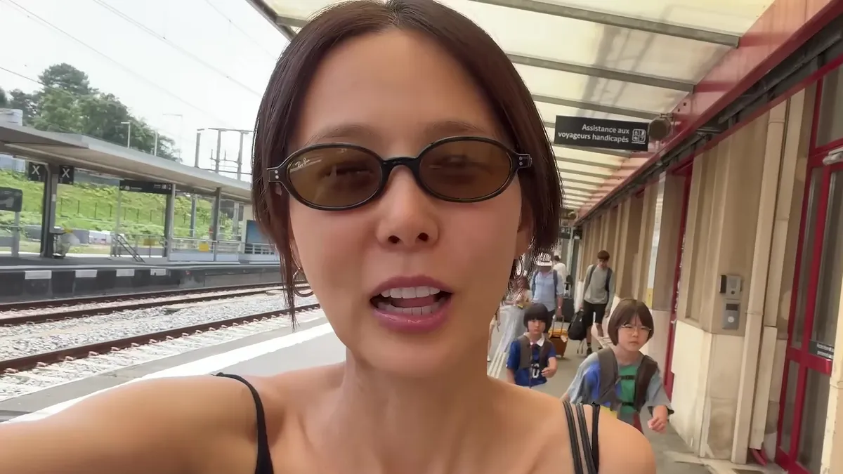Kim Na-young habla ante la cámara mientras se desplaza por el andén de una estación de tren en Francia