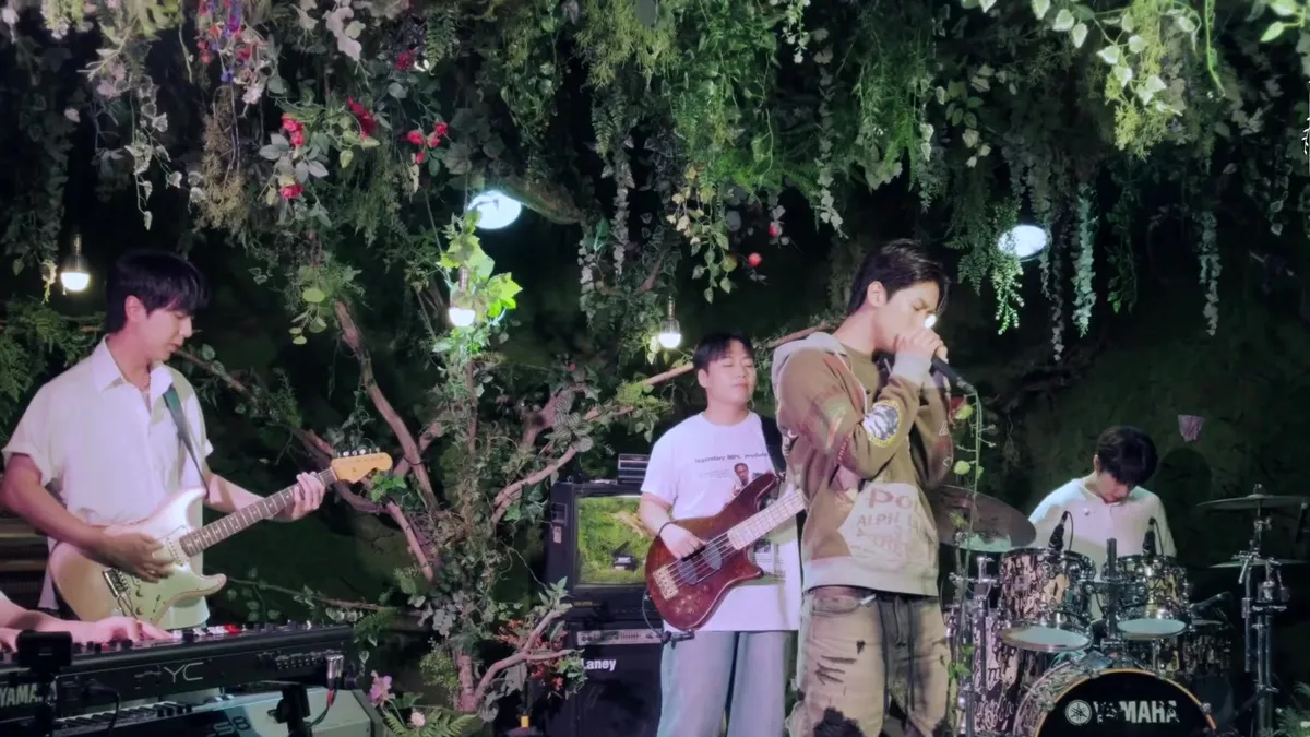 Big Naughty presenta una interpretación en vivo de 'Nostalgia' junto a una banda en un escenario con concepto de bosque