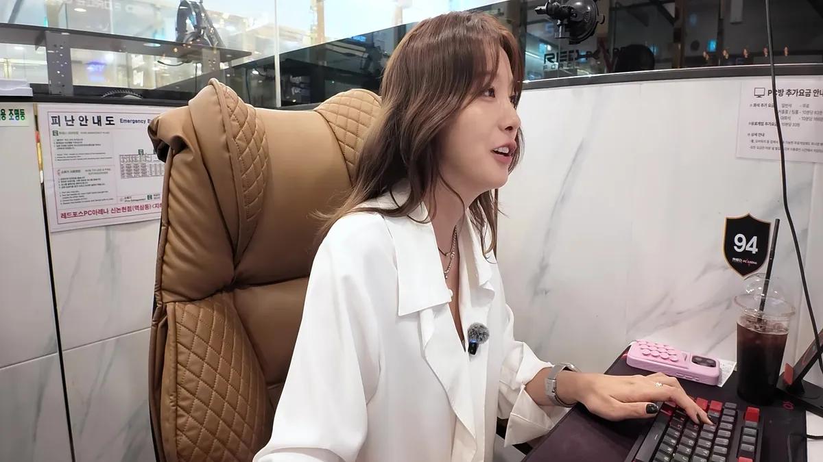 Yoo In-young conversando mientras observa la pantalla de un juego en un asiento de un PC bang